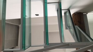 Una escalera con barandillas de vidrio y un pilar de madera.