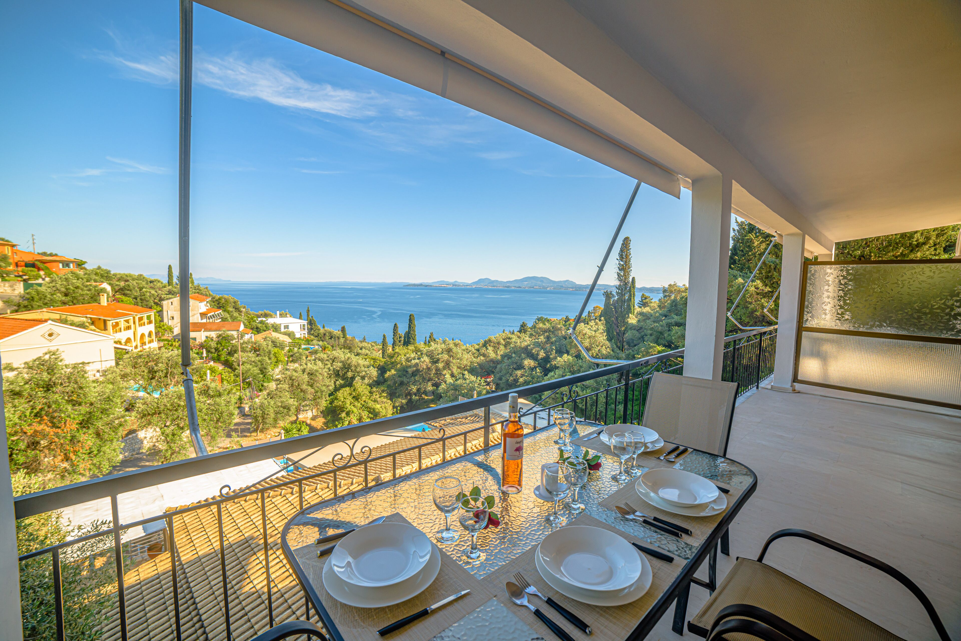 Una mesa de comedor en un balcón con vista despejada al mar y al paisaje circundante.