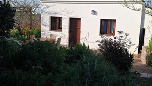 Un bâtiment blanc avec un toit recouvert de tuiles, deux fenêtres et une porte.