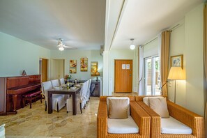 Un comedor con un piano, un sofá y una mesa para cuatro personas.