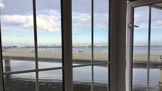 A view through a window with a view of a bridge over water, a road, and distant buildings. - Comfy 1 Bed Cardiff Bay Flat With Water Views- WiFi, Millenium Stadium Rugby (Cardiff)