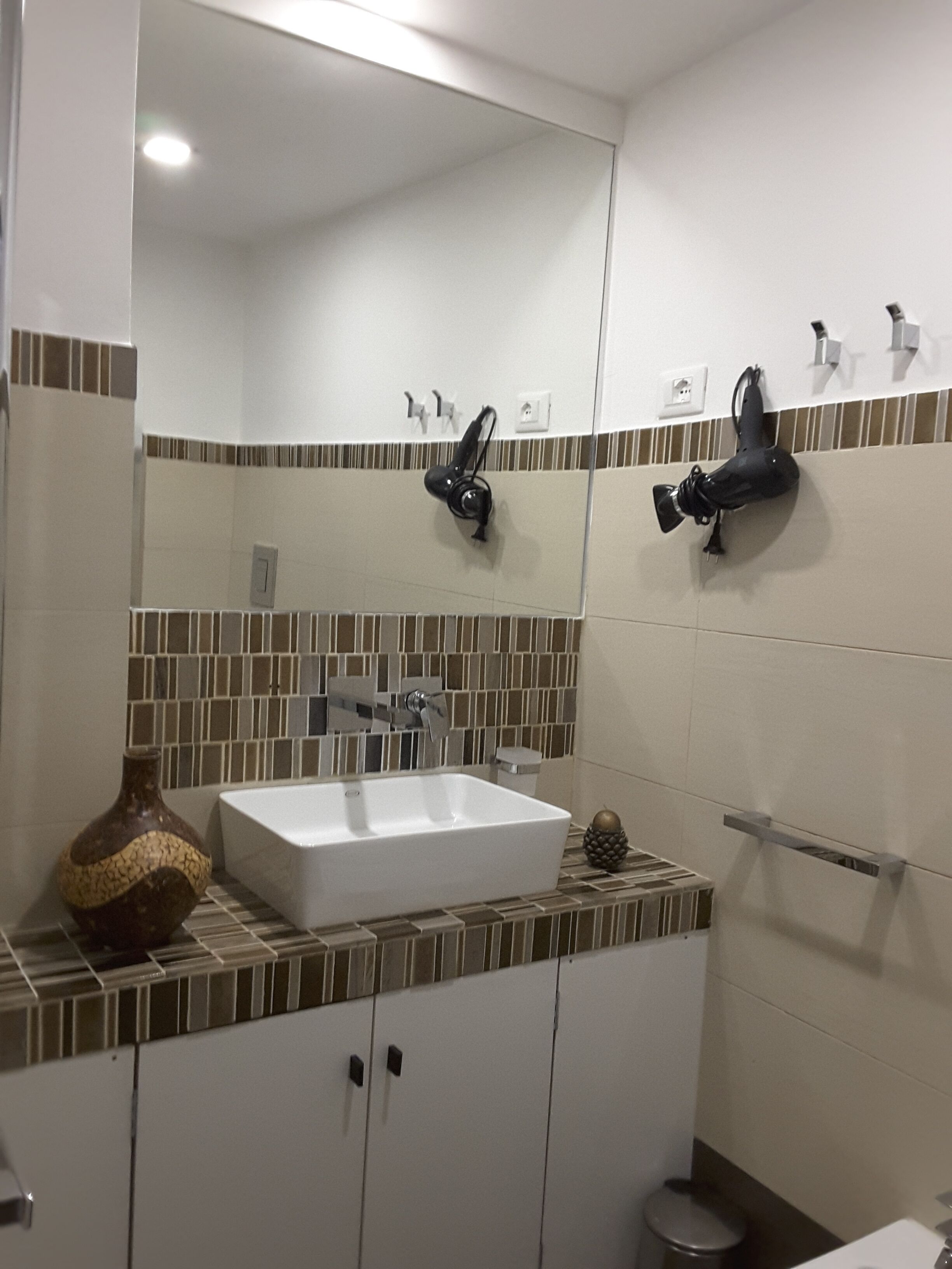 Une salle de bain avec un lavabo blanc, un miroir et un porte-serviettes.