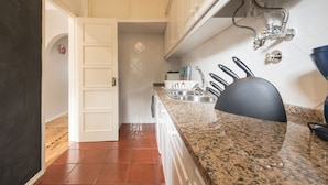 A kitchen with white cabinets, a granite countertop, a sink, and a black chair. - The ideal place near the Castle * 2BD APT CENTRAL * (Lisboa)
