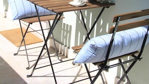 A small outdoor seating area with a wooden table and two chairs, a potted plant, and a lantern on the table. - The ideal place near the Castle * 2BD APT CENTRAL * (Lisboa)