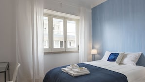A hotel room with a bed, a window, a chair, and a table. - The ideal place near the Castle * 2BD APT CENTRAL * (Lisboa)