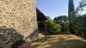 A stone building with a covered porch and a tall tree in the background. -  Authentic Massa Marittima Get Away 220 sqm in the Tuscan countryside  (Massa Marittima)