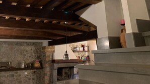 A rustic interior with exposed wooden beams, a stone fireplace, and a balcony with a wrought iron railing. -  Authentic Massa Marittima Get Away 220 sqm in the Tuscan countryside  (Massa Marittima)