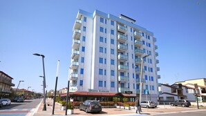 A multi-story hotel with balconies, a restaurant at the ground level, and a clear blue sky.