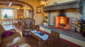 A cozy living room with a fireplace, leather armchair, and a dining area with a table and chairs.