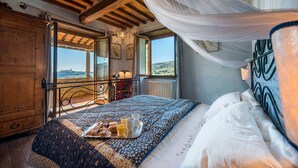 A bedroom with a large bed, a tray of breakfast, and a view of the countryside.