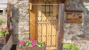 A stone building with a wooden door, a small wooden mailbox, and flower boxes with pink flowers. - House in quiet village. Ideal couples, and friends, in Noceda del Bierzo León. (Noceda Del Bierzo León)