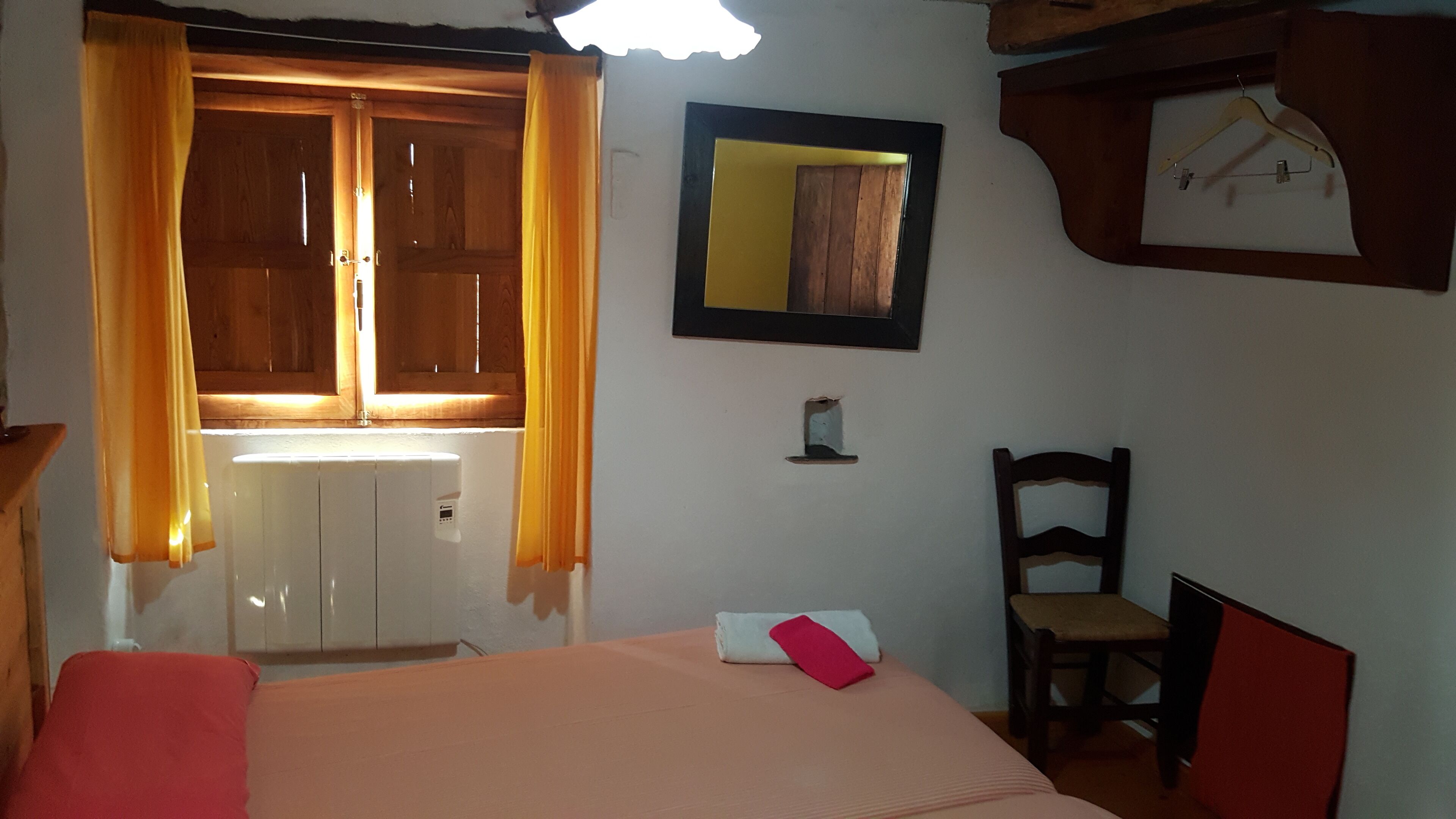 Un dormitorio con cama, un armario de madera, un espejo y una silla.