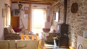 A rustic room with a stone wall, wooden furniture, a fireplace, and a television. - House in quiet village. Ideal couples, and friends, in Noceda del Bierzo León. (Noceda Del Bierzo León)