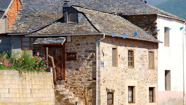A stone building with a sloped roof, a wooden bench, and a small garden with flowers. - House in quiet village. Ideal couples, and friends, in Noceda del Bierzo León. (Noceda Del Bierzo León)