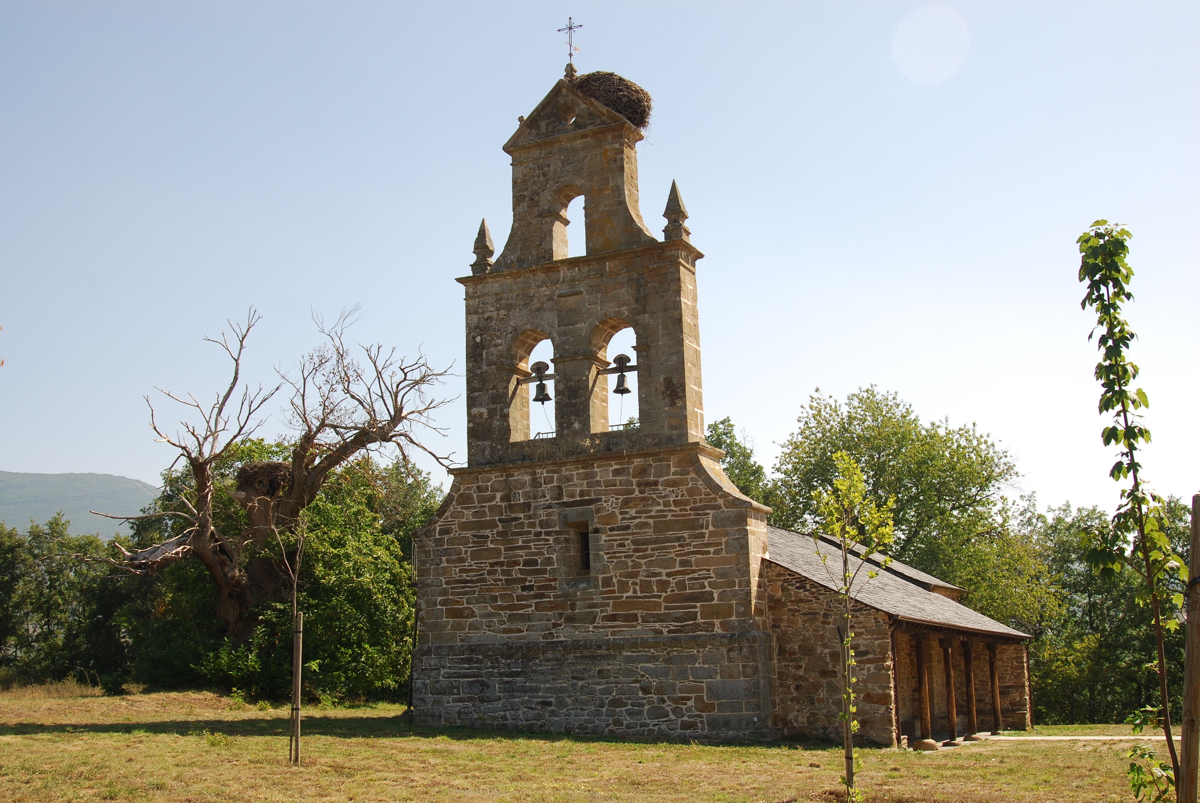 A stone church with a bell tower and a cross on top.