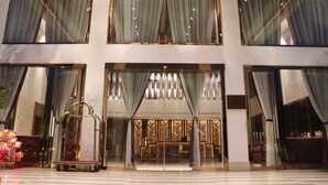 A hotel lobby with large windows, a reception desk, and a chandelier. - Chang Palace Vientiane (Vientiane)
