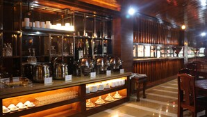 A bar area with shelves of bottles, glasses, and a buffet counter with plates and glasses. - Chang Palace Vientiane (Vientiane)