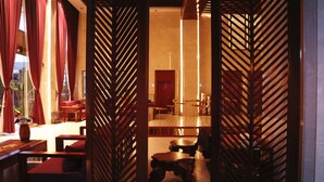 A traditional room with a wooden partition, a sofa, a small table, and a decorative vase. - Chang Palace Vientiane (Vientiane)