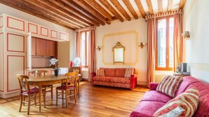 A cozy living room with a wooden dining table, chairs, a sofa, and a loveseat. - APARTMENT VENICE SAN MARCO "TINTORETTO" (Venezia)
