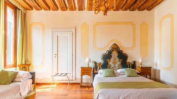 A hotel room with two beds, wooden flooring, a chandelier, and a door. - APARTMENT VENICE SAN MARCO "TINTORETTO" (Venezia)