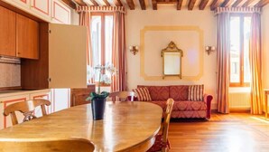 A dining area with a wooden table and chairs, a red sofa, and a potted orchid. - APARTMENT VENICE SAN MARCO "TINTORETTO" (Venezia)