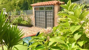 A patio area with a stone floor, a small brick structure with a tiled roof, and a metal gate. - LA CASA DEL RÍO. Ideal for families with children and couples seeking tranquility (Pujayo)