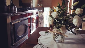 A kitchen with a vintage stove, a washing machine, and a vase with flowers on a table.