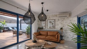 A modern living room with a brown sofa, two round tables, and hanging light fixtures. - Villa Arai   (Playa Blanca)