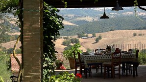 A dining area with a table set for two, overlooking a hilly landscape. - Charming Maremma Villa w/Swimming Pool, Countryside Serenity and Beaches Nearby (Magliano in Toscana)