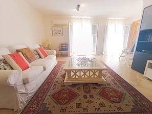 A living room with a sofa, a coffee table, a patterned rug, and a bookshelf.