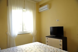 A bedroom with a bed, a dresser, a television, and an air conditioner. - CAMPANA HOUSE CENTRAL STATION NAPLES (Napoli)
