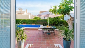 An outdoor patio with a pool, a table with chairs, and potted plants. - Two Bedroomed Villa With Private Pool. (Torrevieja)