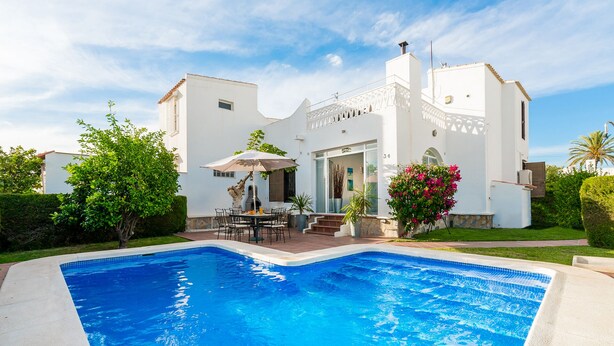 A modern white house with a swimming pool, outdoor dining area, and lush greenery. - Two Bedroomed Villa With Private Pool. (Torrevieja)