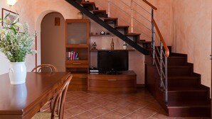 A living room with a wooden staircase, a TV, and a bookshelf. - Terrazza del Centro (Cefalù)