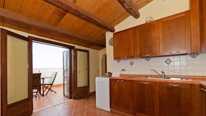 A kitchen with wooden cabinets, a tiled backsplash, and a built-in dishwasher. - Terrazza del Centro (Cefalù)