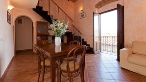 A dining area with a wooden table and chairs, a staircase, and a balcony with a railing. - Terrazza del Centro (Cefalù)