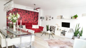 A modern living room with a red sofa, a glass dining table, and a ceiling fan. - beautiful, quiet, great apt downtown, near the beach. Ask for parking (Alicante)