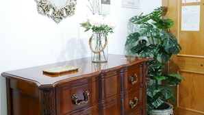 A wooden dresser with drawers, a mirror, a vase with flowers, and a potted plant. - beautiful, quiet, great apt downtown, near the beach. Ask for parking (Alicante)