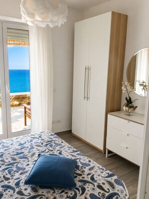 Ein Schlafzimmer mit Bett, Kleiderschrank, Kommode, Spiegel und Meerblick.