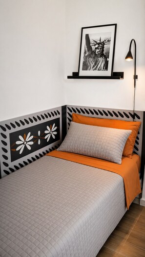 Een net opgemaakt bed met een beddegoed met een patroon, een kussen en een oranje deken.