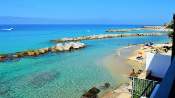 Ein Strand mit klarem türkisblauem Wasser, steinernen Wellenbrechern und einigen Sonnenanbetern.