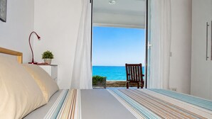 A bedroom with a bed, a chair, and a view of the ocean. - 10 meters from the beach – Marina Holiday Home, oceanfront in Pizzo, Calabria (Pizzo)