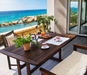 A wooden table with a kettle, cups, and a glass of orange juice on a balcony overlooking the sea. - 10 meters from the beach – Marina Holiday Home, oceanfront in Pizzo, Calabria (Pizzo)