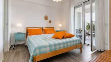 A bedroom with a wooden bed, two bedside tables with lamps, a checkered bedspread, and a view of an outdoor patio.