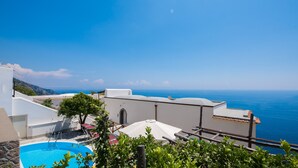 Une piscine sur le toit offrant une vue dégagée sur la mer et un bâtiment blanc doté d’un balcon.