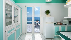 Une cuisine avec vue sur la mer, un réfrigérateur et un coin repas comprenant une table et des chaises.