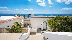 Un bâtiment blanc avec vue sur la mer, un escalier et quelques plantes.