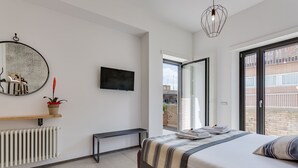 Une chambre moderne avec un grand lit, une télévision, un miroir et une vue sur l’extérieur.