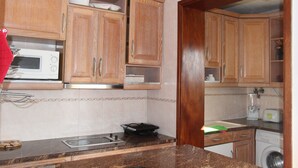 A kitchen with wooden cabinets, a microwave, a toaster, and a washing machine. - At 300 m from the beach, a 2 bedroom penthouse with an amazing terrace.  Center, cable tv (Albufeira)