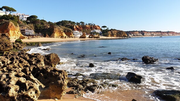 A coastal beach with rocky formations, clear blue water, and buildings on the hillside. - At 300 m from the beach, a 2 bedroom penthouse with an amazing terrace.  Center, cable tv (Albufeira)